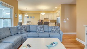 A modern living room with a sectional sofa, a white coffee table, and a kitchen in the background.