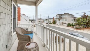A balcony with wicker furniture and a view of a residential street.