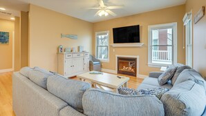 A living room with a sofa, a coffee table, a television, a fireplace, and a ceiling fan.