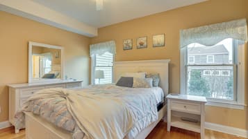A bedroom with a bed, bedside tables, a dresser, a window with a view, and wall decorations.