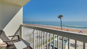 A balcony with a view of the beach, a palm tree, and a chair. - Beachfront Daytona Vacation Rental w/ Balcony (Daytona Beach)