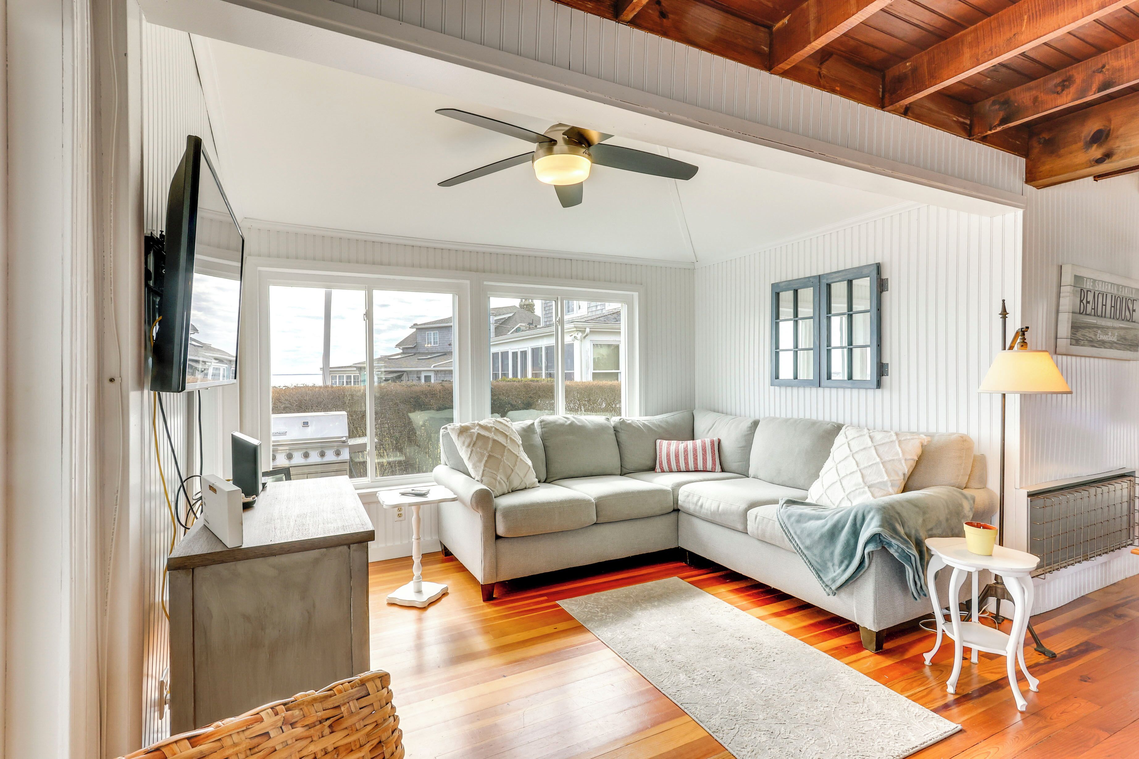 A spacious living room with a large sectional sofa, a ceiling fan, and a view of the outside.