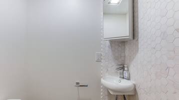 A bathroom with a white toilet, a sink with a mirror above it, and a hexagonal patterned wall.
