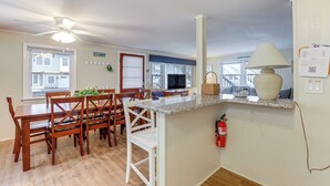 Un comedor con mesa y sillas de madera, una encimera de cocina y un ventilador de techo.