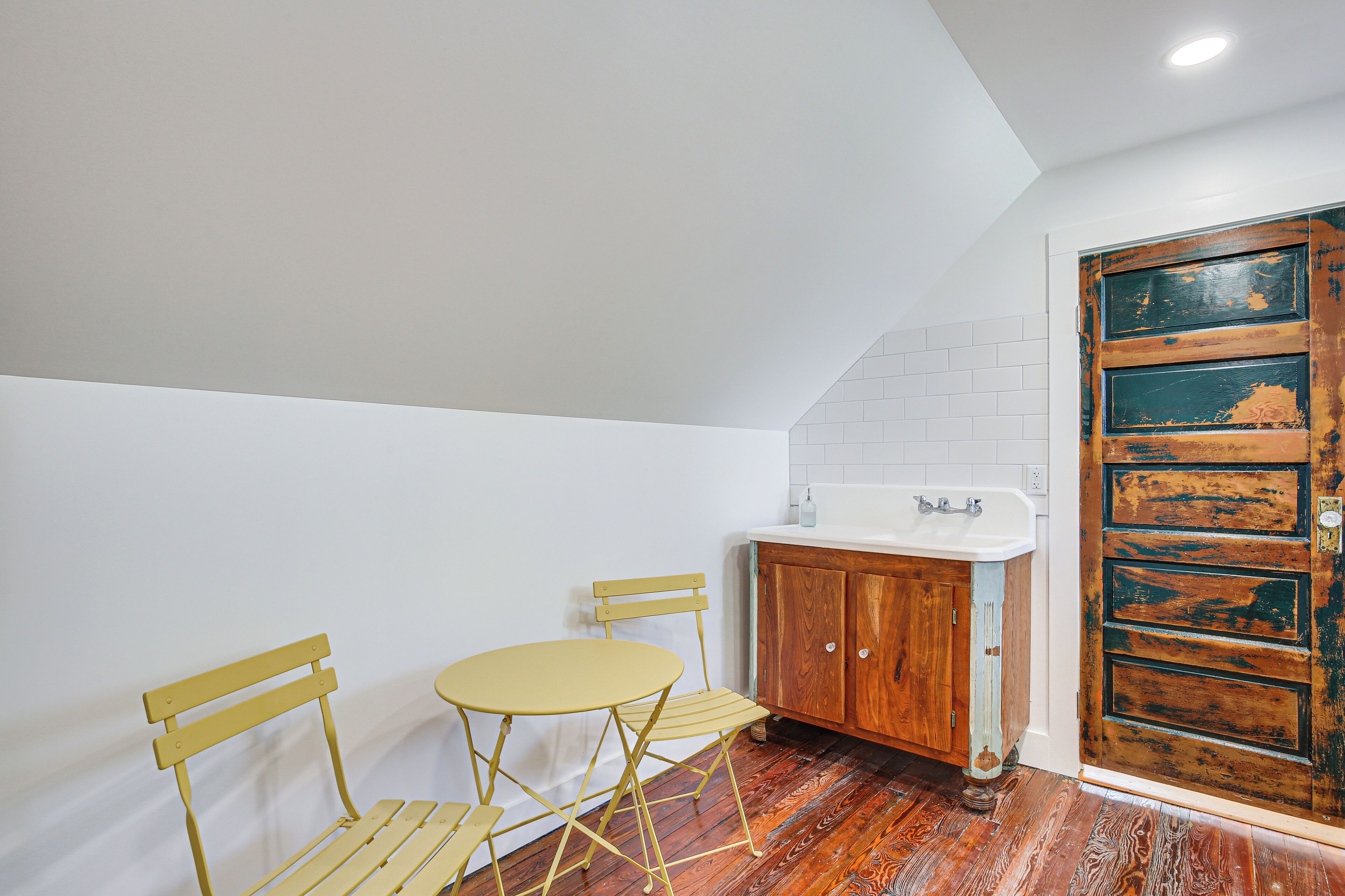A small kitchen with a wooden cabinet, a sink, and a yellow table with chairs.