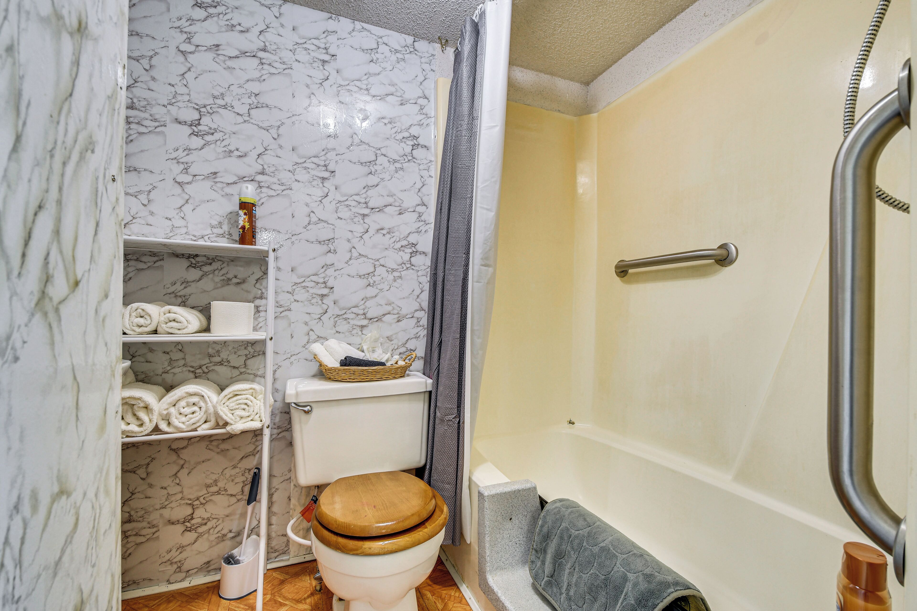 Un baño con inodoro, ducha y paredes de mármol.