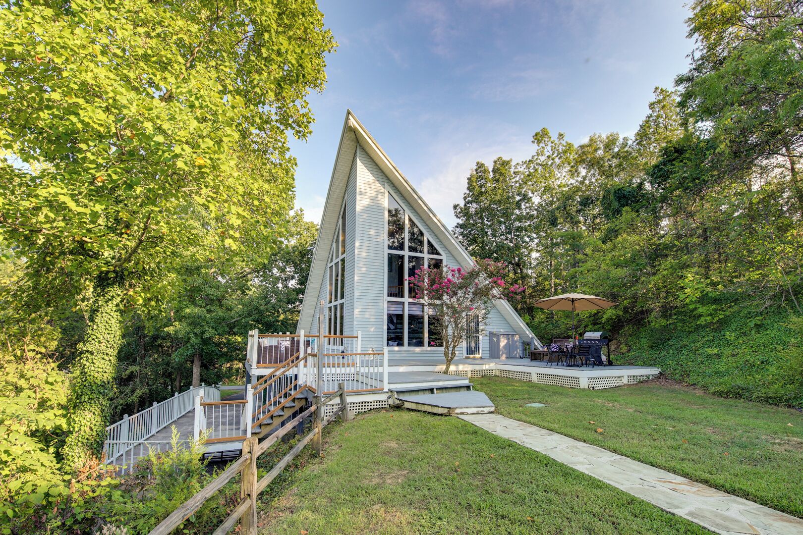 A modern house with a triangular roof, a deck, and a staircase leading to a porch.