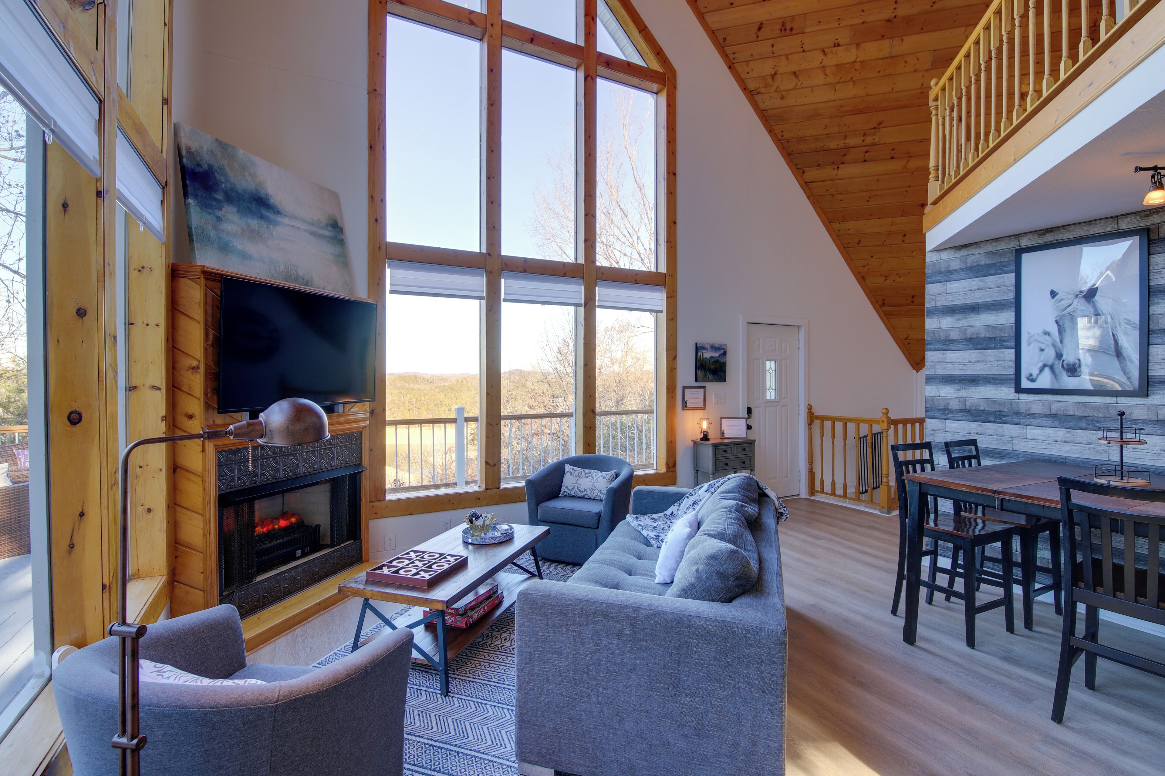 A spacious living area with a fireplace, large windows, and a dining area with wooden furniture.