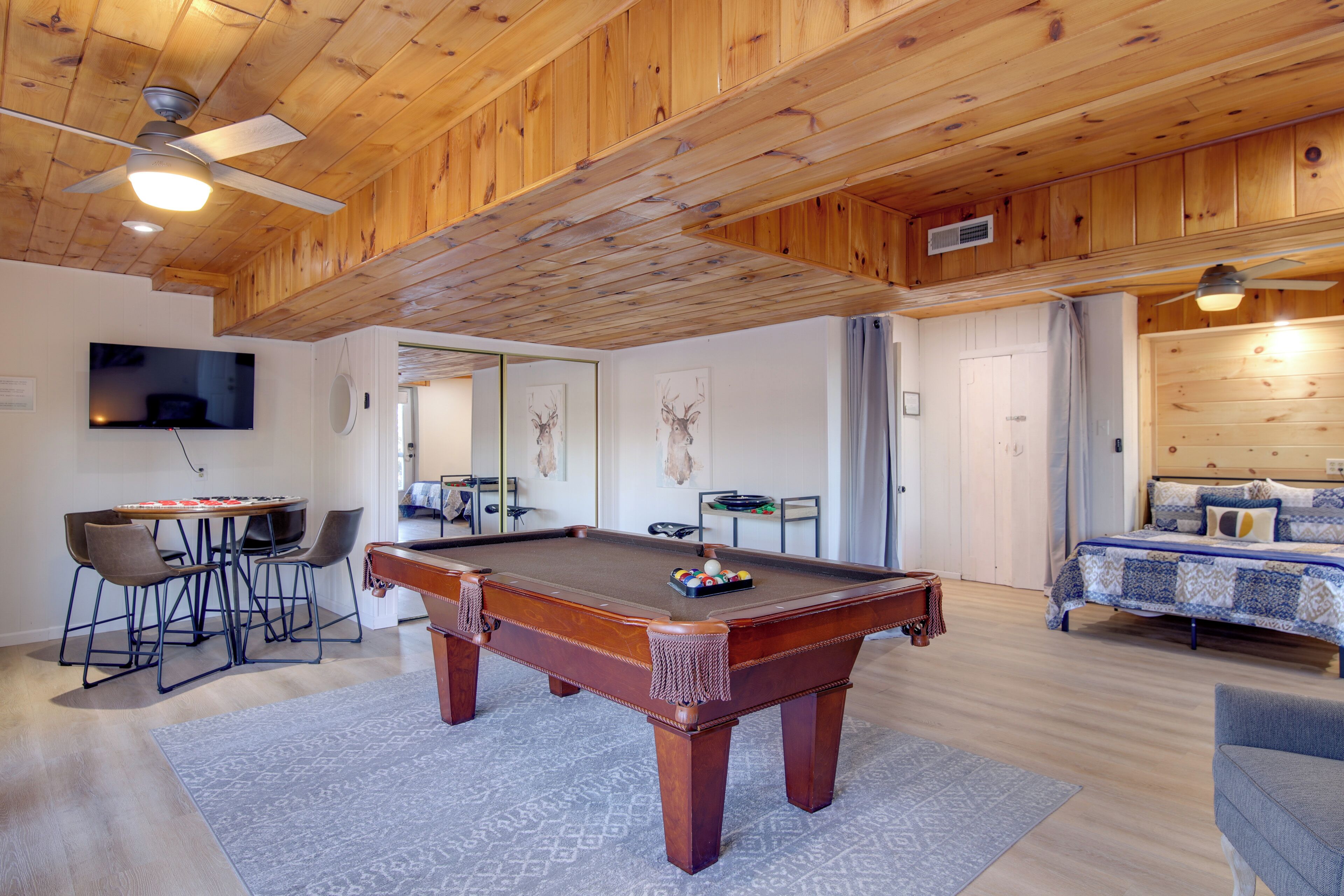 Una habitación con paneles de madera, una mesa de billar, una cama y un televisor.