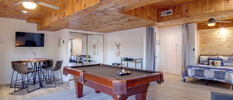 Una habitación con paneles de madera, una mesa de billar, una cama y un televisor.