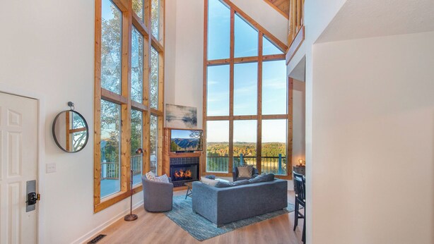 A spacious living room with large windows, a fireplace, and a cozy seating area. - Smoky Mountains Cabin w/ Lake Access & Game Room! (Sevierville)