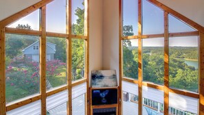 A corner room with large windows offering views of a house and a lake surrounded by trees. - Smoky Mountains Cabin w/ Lake Access & Game Room! (Sevierville)