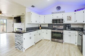 Een moderne keuken met witte kasten, een zwart aanrecht-eiland, een magnetron, een oven en een koffiezetapparaat.