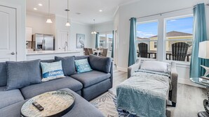 A modern living room with a gray sofa, a round coffee table, and a bed with a blue blanket. - Pelican Reef Or104 3 Bedroom Home by RedAwning (Rockport)