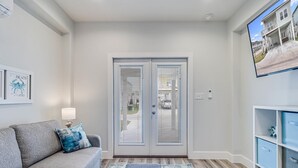 A modern living room with a grey sofa, a patterned rug, and a glass door leading outside. - Pelican Reef Or104 3 Bedroom Home by RedAwning (Rockport)