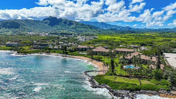 A coastal resort with beachfront properties, lush greenery, and mountainous backdrop.