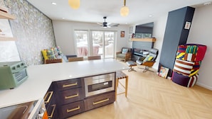 A modern kitchen with a central island, a dining area with chairs, a sofa, and a TV mounted on the wall. - On Lake. Walk to Marina, Concerts, Parks, Dining. Hip Updated Unit. Big Yard (Dillon)