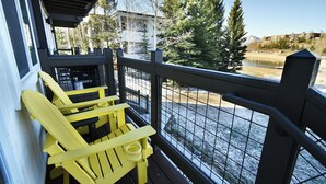 A balcony with yellow Adirondack chairs, a metal railing, and a view of a lake and trees. - On Lake. Walk to Marina, Concerts, Parks, Dining. Hip Updated Unit. Big Yard (Dillon)
