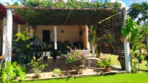 A covered patio area with potted plants and a wooden pergola. - Pousada Águas da Chapada (Carolina)