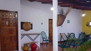A room with a wooden door, a wall-mounted round mirror, a white pillar, and several green chairs. - Pousada Águas da Chapada (Carolina)