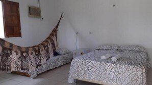 A bedroom with a bed, a sofa, and a hanging chair. - Pousada Águas da Chapada (Carolina)