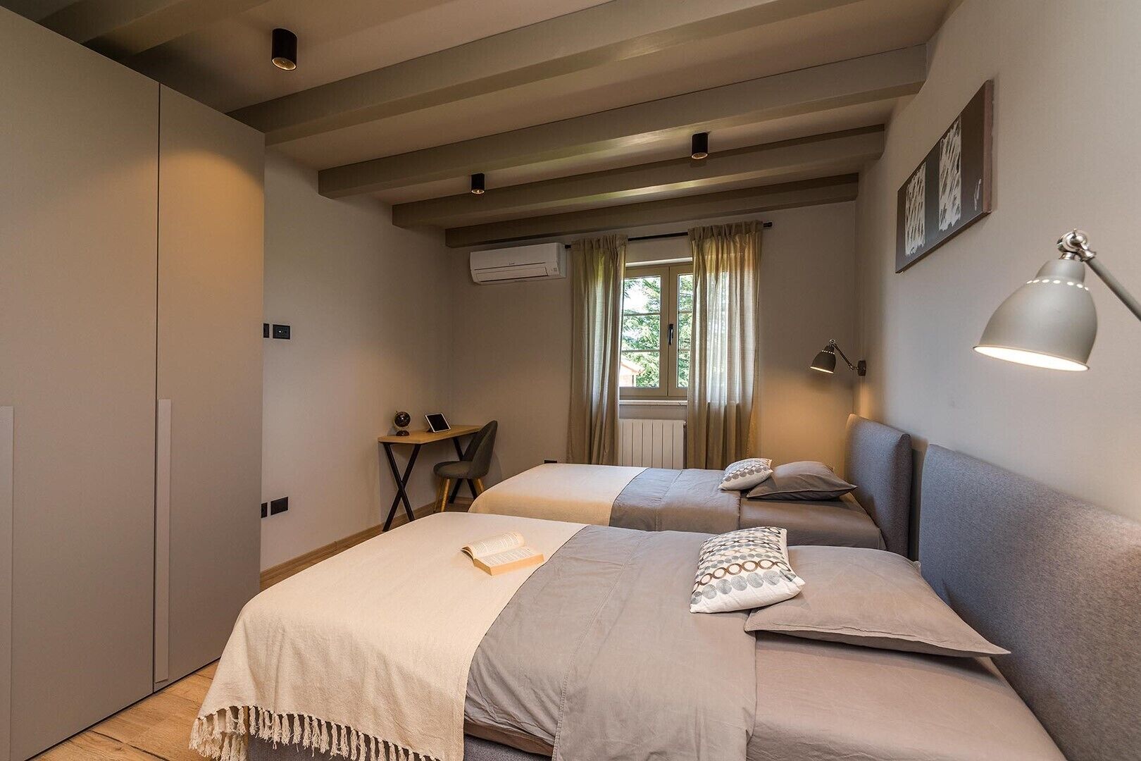 A bedroom with two beds, a desk, and a chair.