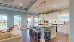 A modern kitchen with white cabinets, a central island with stools, and pendant lighting. - Salty Sea House: 3  BR, 2  BA House in Crystal Beach , Sleeps 12 (Bolivar Peninsula)