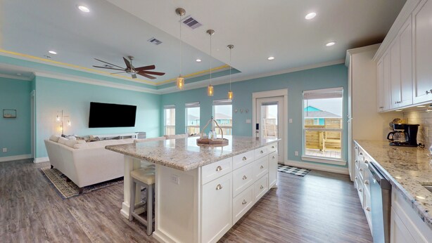 A modern kitchen with a central island, white cabinetry, and a ceiling fan. - Salty Sea House: 3  BR, 2  BA House in Crystal Beach , Sleeps 12 (Bolivar Peninsula)