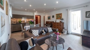A modern living room with a sofa, coffee table, and a dining area with chairs and a table. - Apartments Meri & Karla (Dubrovnik)