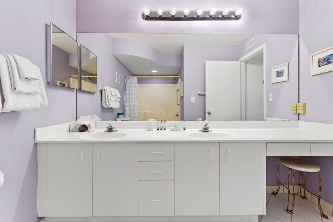 Un baño con dos lavamanos, un espejo grande y un mueble de tocador con cajones.