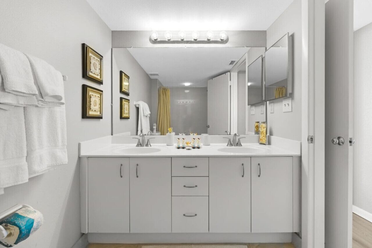 A modern bathroom with two sinks, a vanity, and a large mirror.