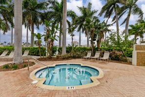 A swimming pool with lounge chairs and palm trees.