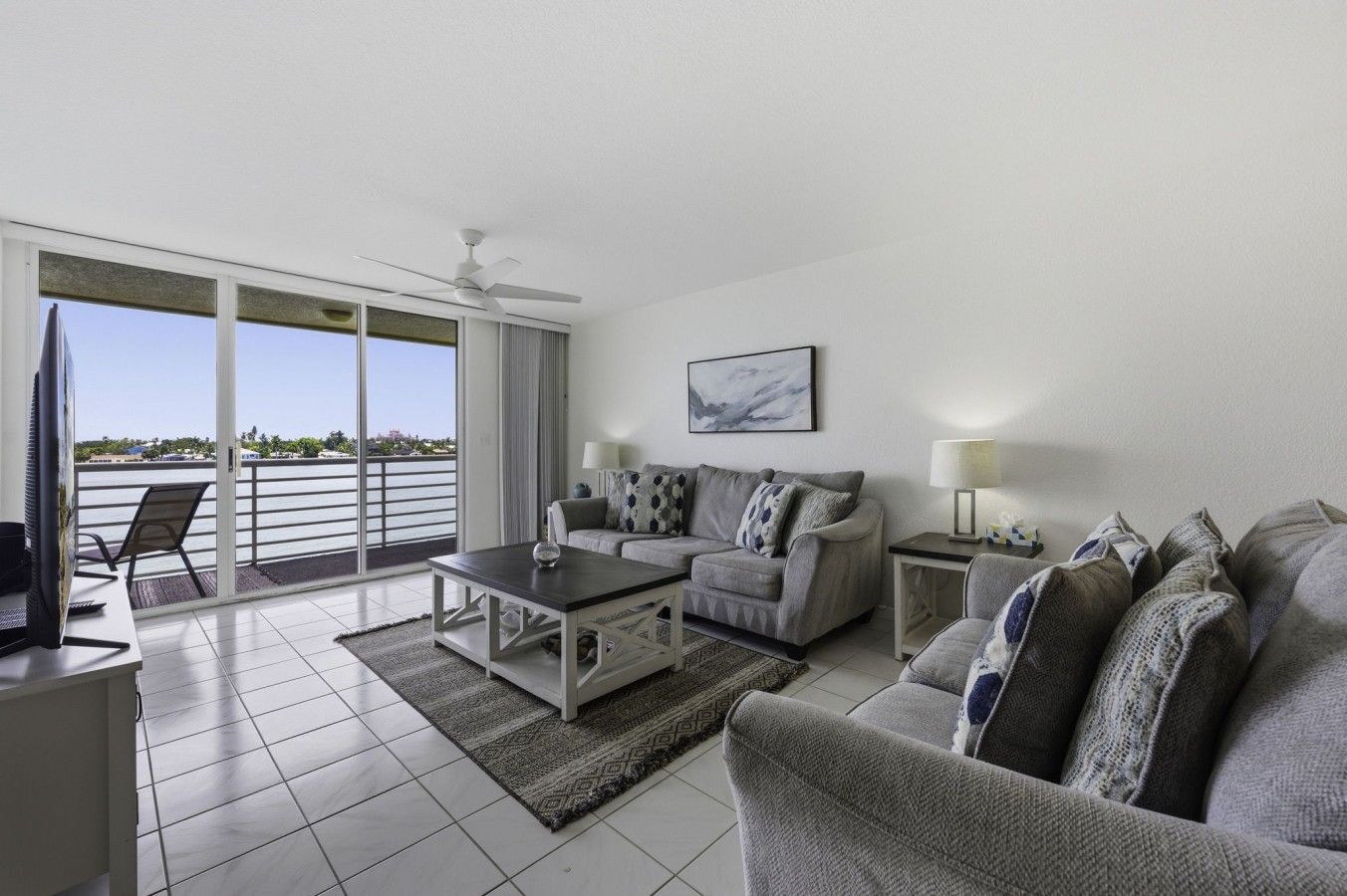 Un salon avec un canapé, une table basse, un téléviseur et un balcon offrant une vue agréable.