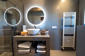 Enjoy a refreshing bathroom experience with a sleek vanity, sink, and convenient towel warmer.