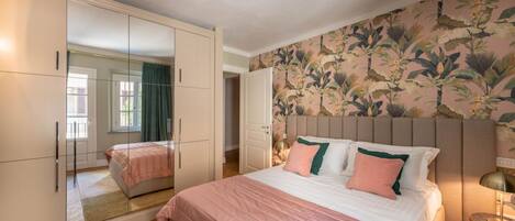 A bedroom with a large bed, a wardrobe with a mirror, and a floral wallpaper.