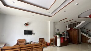 Amplio salón con un banco de madera, un televisor montado en la pared, una escalera y un mostrador de recepción.