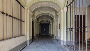 A corridor with a dark wooden door at the end, flanked by metal railings and a tiled floor. - La Corte by Wonderful Italy (Torino)