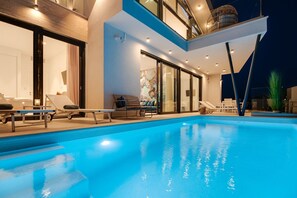 Relax by the rectangular pool surrounded by lounge chairs and sunbeds, offering stunning views of the surrounding landscape.