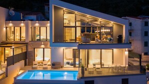 A modern two-story house with a swimming pool, large windows, and outdoor seating. - Villa Flower with 3 en-suite bedrooms, heated pool, sea views (Jesenice)