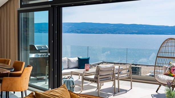 A modern outdoor seating area with a view of a large body of water and distant hills. - Villa Flower with 3 en-suite bedrooms, heated pool, sea views (Jesenice)