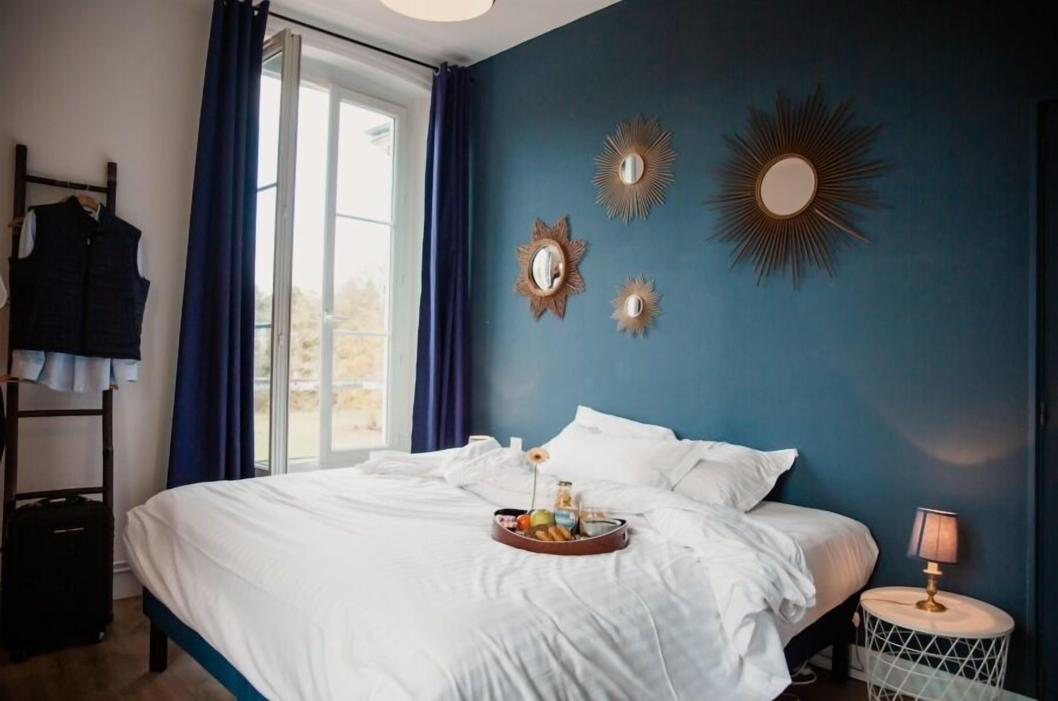 A bedroom with a bed, a tray of breakfast items, a lamp, and wall decorations.