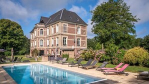 Un grande edificio storico con piscina e lettini prendisole.