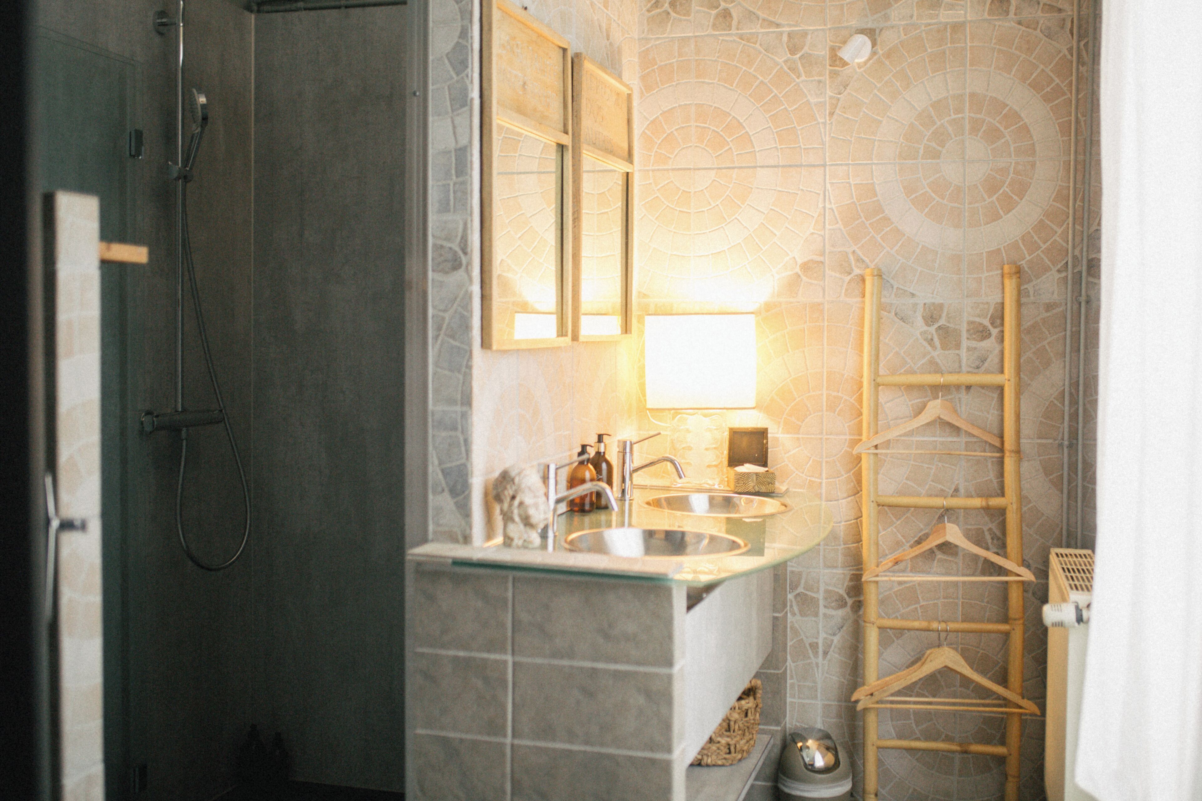 Un baño con cabina de ducha de vidrio, lavamanos con espejo y un toallero de madera.
