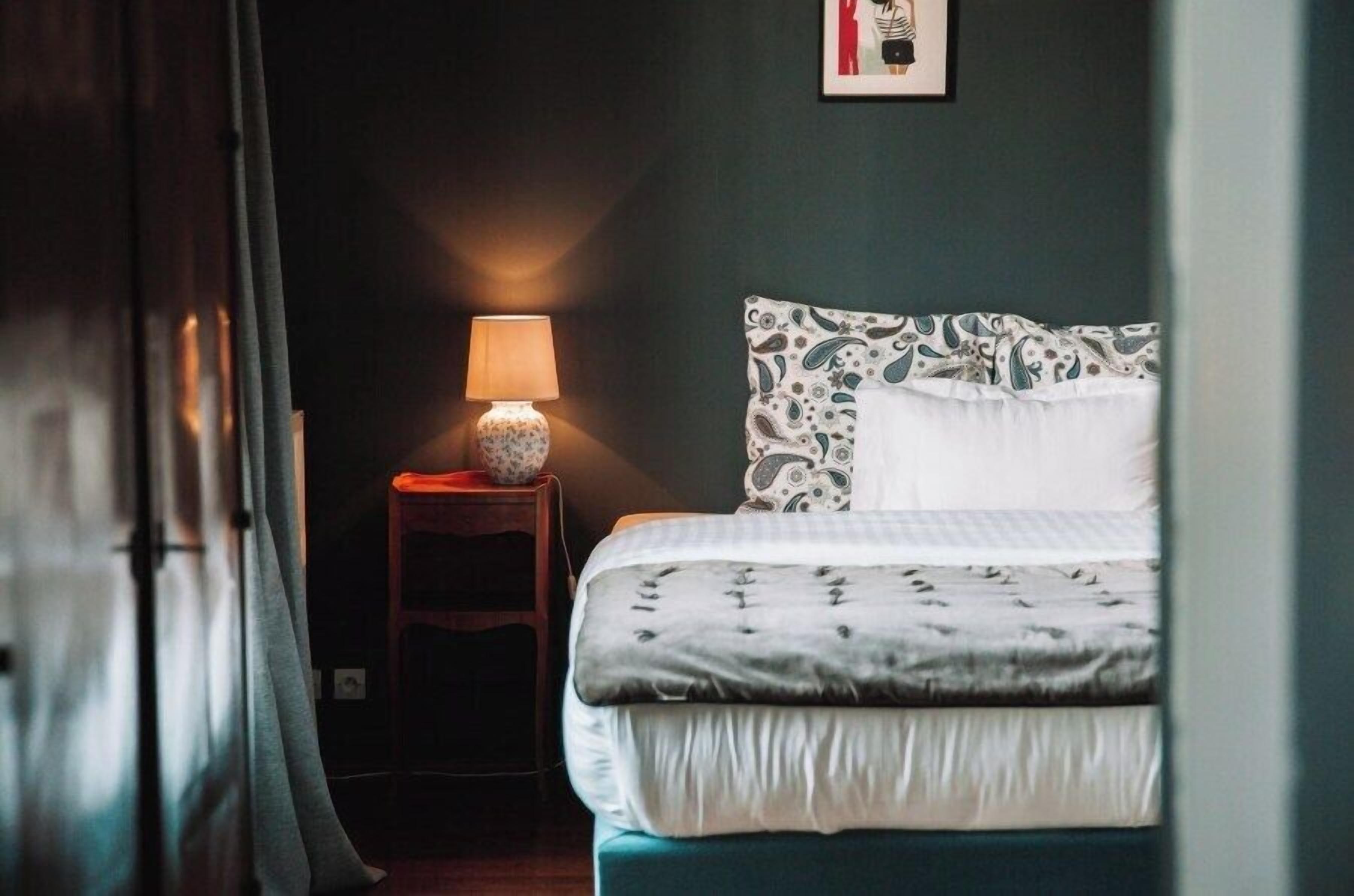 A bedroom with a bed, a bedside lamp, and a framed picture on the wall.