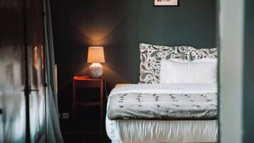 A bedroom with a bed, a bedside lamp, and a framed picture on the wall.