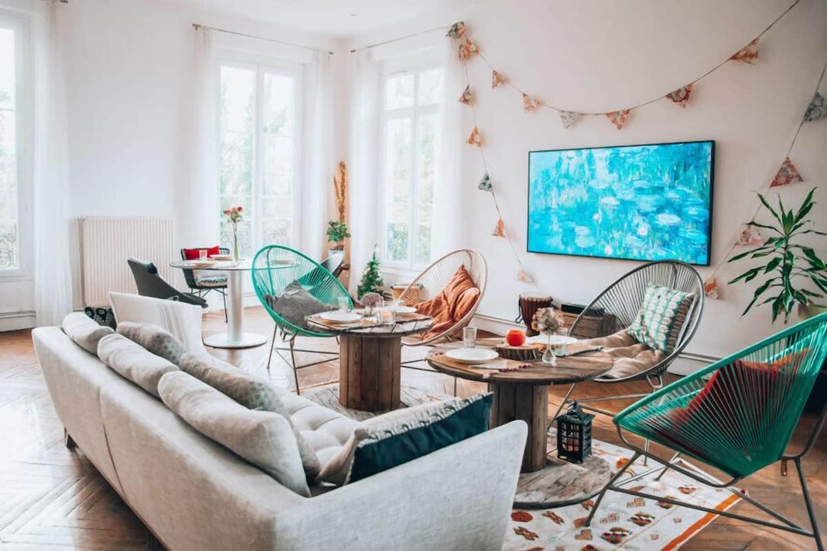 Ein modernes Wohnzimmer mit einer Couch, Sesseln, einem Esstisch und einem großen Gemälde.