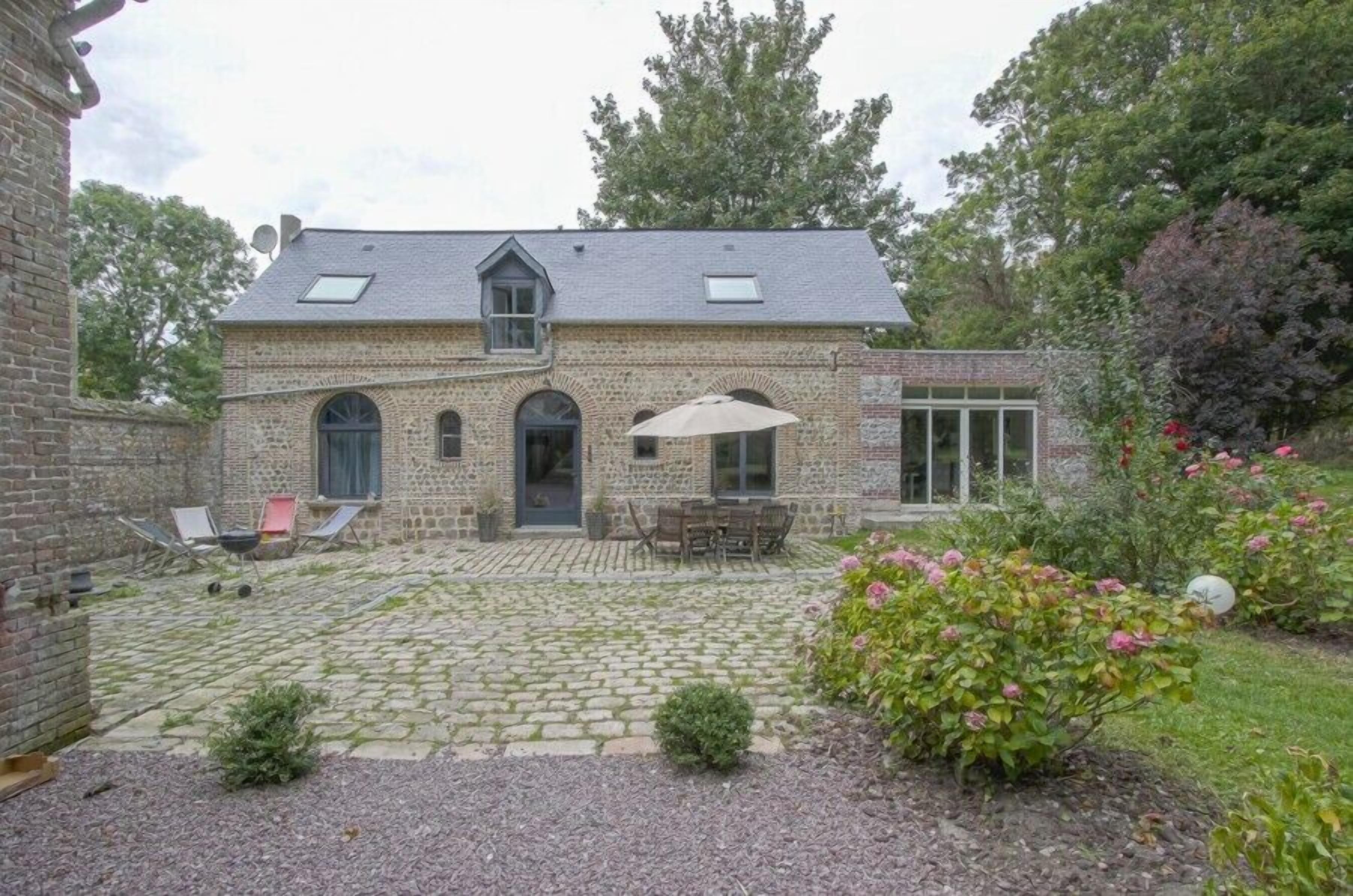 A stone house with a courtyard, a covered patio, and a garden with flowers.