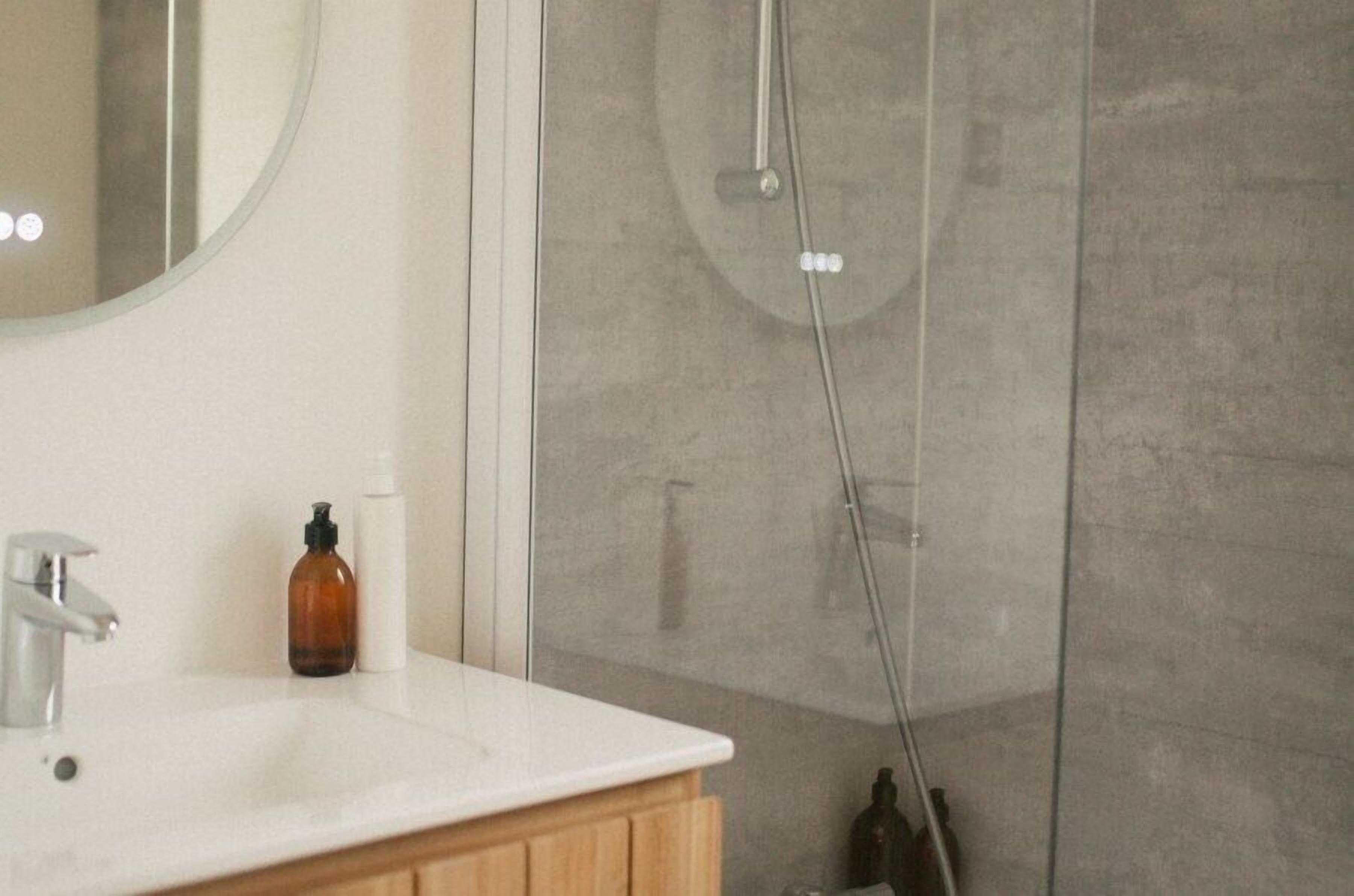 Une salle de bain avec un lavabo blanc, un miroir et un espace douche.