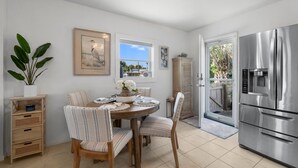 Un coin repas avec une table ronde, des chaises à rayures, un buffet en bois et un grand réfrigérateur.
