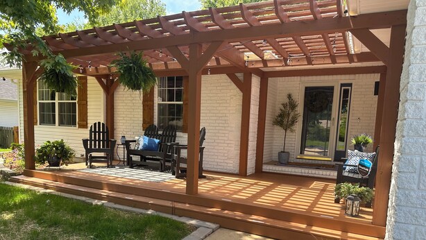 A covered patio with outdoor furniture, a pergola, and a sign indicating a pet-friendly area.